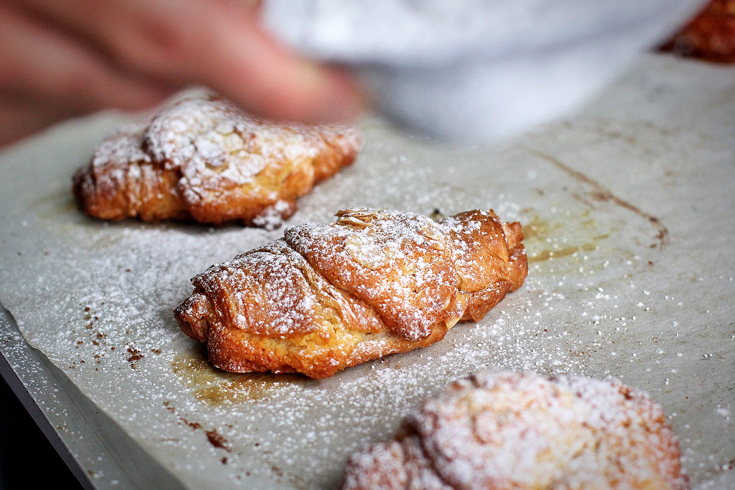 Almond croissants getting dusted with icing sugar
