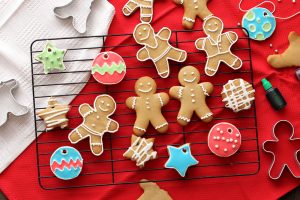 Ginger bread cookies decorated in various ways sit on a cooling rack, on red fabric