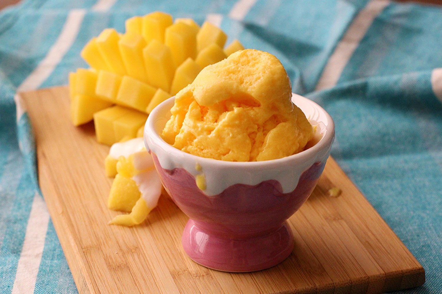 This simple two ingredient recipe makes a thick and creamy frozen yoghurt, in no time at all. Here it's served in an ice cream bowl, with fresh mango on the side.