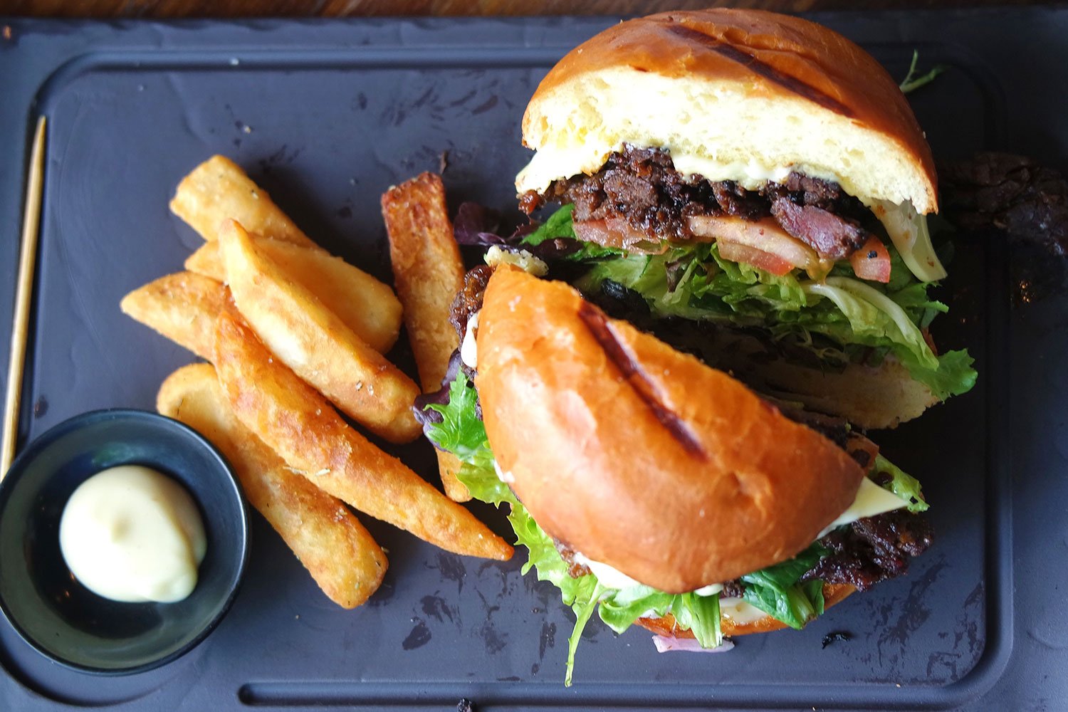 A Korean BBQ Burger with chips and garlic mayo served on a black slate at Miel Burger in Brisbane