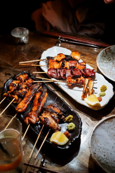A range of yakitori skewers served in a pub-like environment, at night
