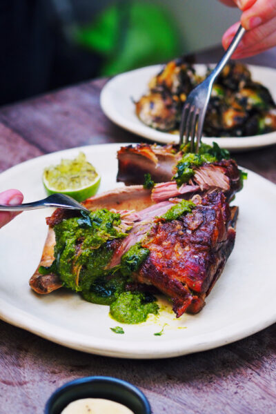 Lamb shoulder with salsa verde getting carved at a restaurant table