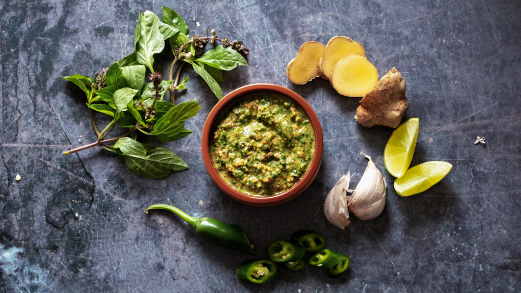 A dish of thai basil pesto surrounded by the ingredients used in the recipe