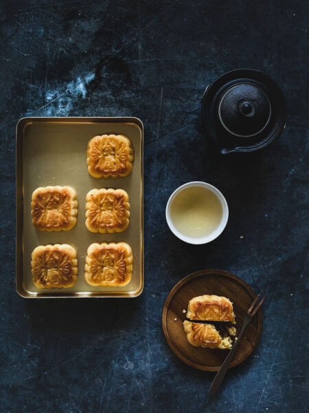 6 mooncakes in a gold box, served with a side of tea.